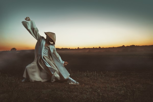 Blonde Asian woman with a long braid doing martial arts in a field in front of a sunrise while holding wooden eggs by Artmood Visualz